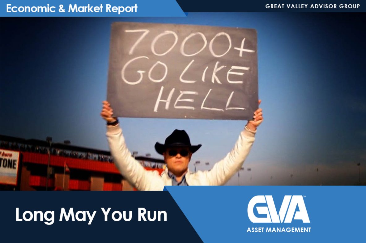 Person in a cowboy hat and sunglasses holds up a large sign that reads '7000+ GO LIKE HELL' at a stadium backdrop.